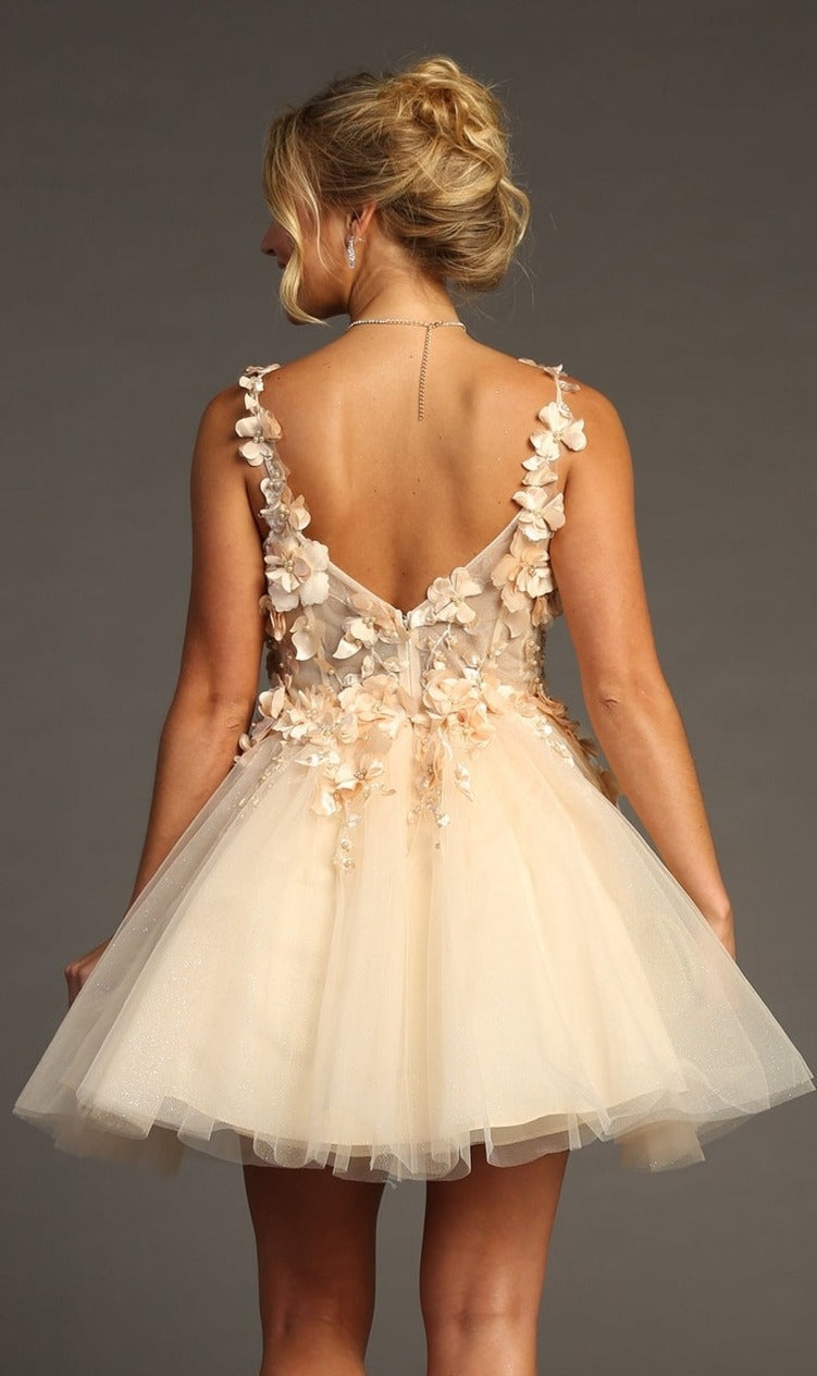 A woman in the Floral-Bodice Short Babydoll Homecoming Dress C321, a sleeveless, backless light beige tulle dress with 3D floral appliqués, stands facing away against a plain backdrop.